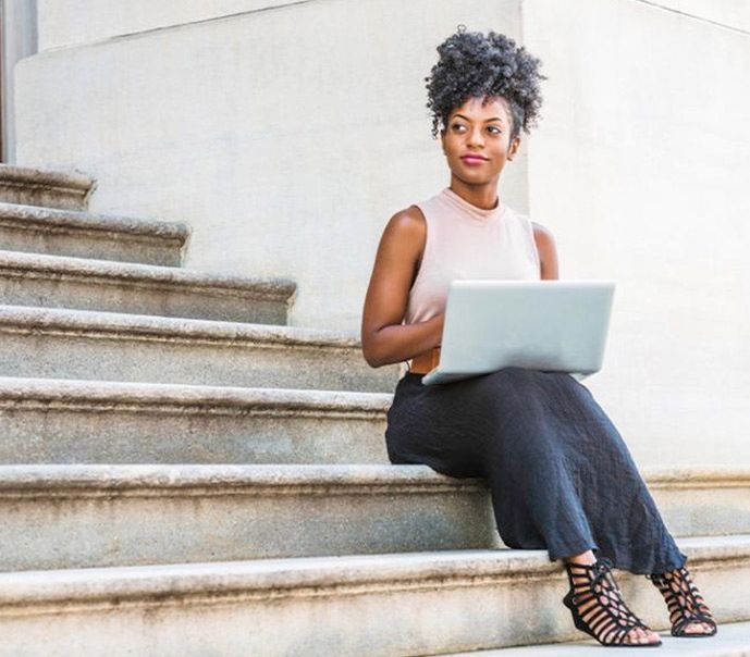 Female college student sitting on stairs with laptop