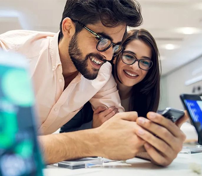 Man and woman looking at a new smartphone in a Spectrum store, smiling
